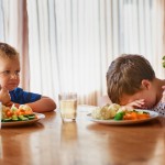 Shot of two unhappy little boys refusing to eat their vegetables at the dinner table